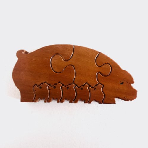 A product picture of an artesanal puzzle made of wood. It is a mother pig feeding her piglets.